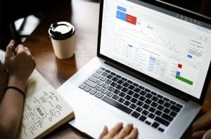image of a modern laptop on a sleek desk, displaying a Google Ads dashboard on the screen