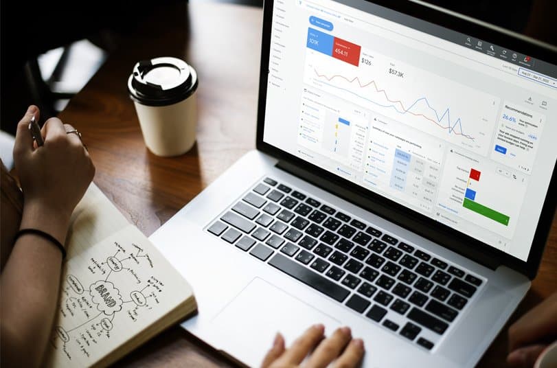 image of a modern laptop on a sleek desk, displaying a Google Ads dashboard on the screen